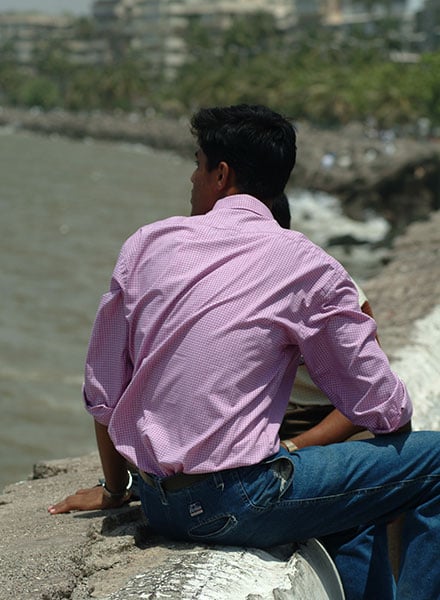 A young man sitting by the water.