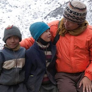 man sitting next to two boys all wrapped in winter clothing in the snow